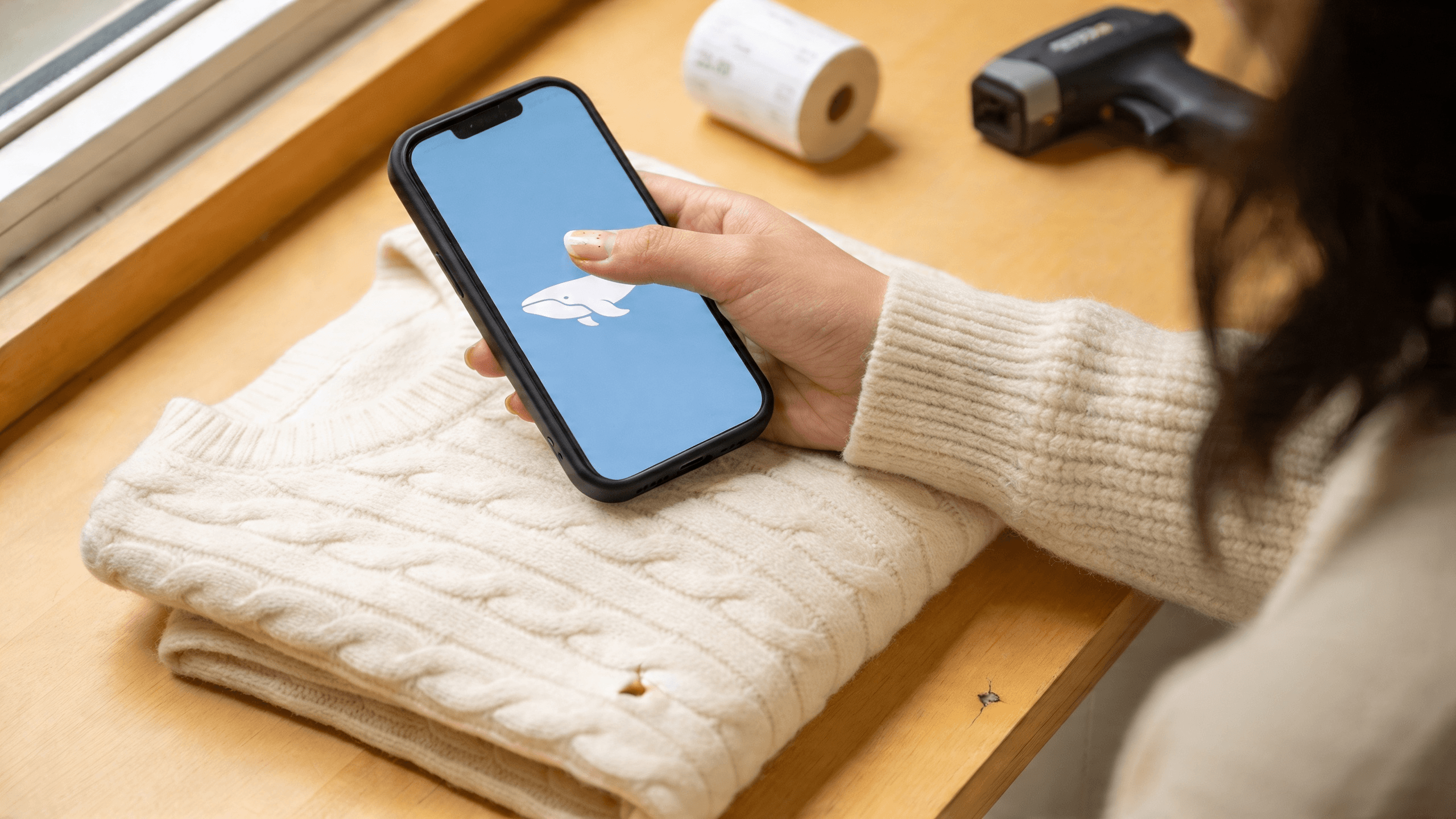InventoryWhale app open on a phone resting on a folded sweater